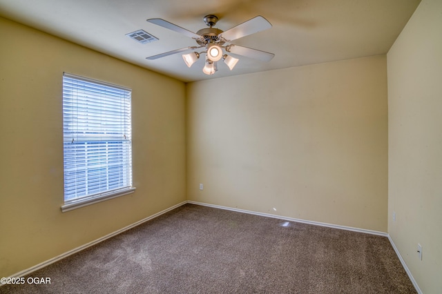 carpeted empty room featuring ceiling fan, visible vents, and baseboards