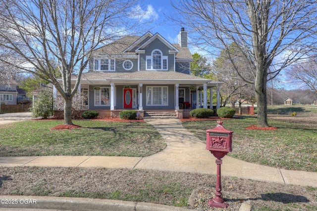 view of front of home featuring a shingled roof, a front yard, covered porch, and a chimney