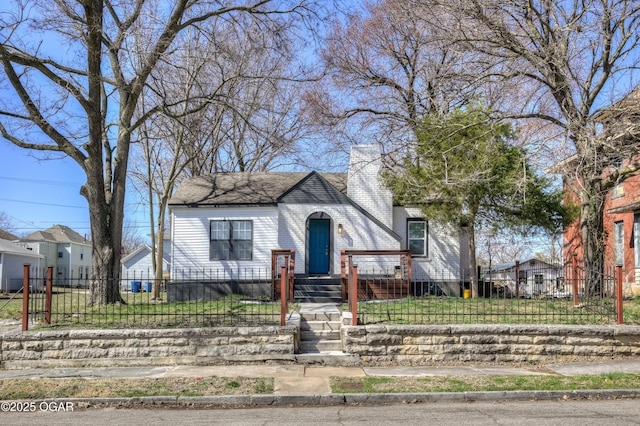 bungalow-style home featuring brick siding, a fenced front yard, and a chimney