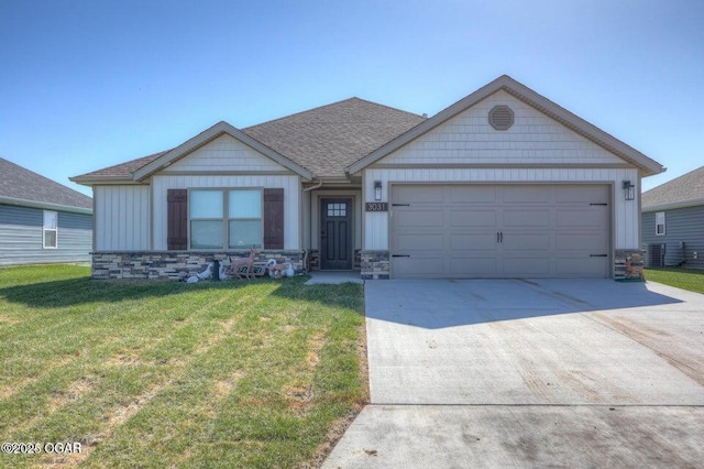 view of front of house with a garage, driveway, a shingled roof, stone siding, and a front lawn