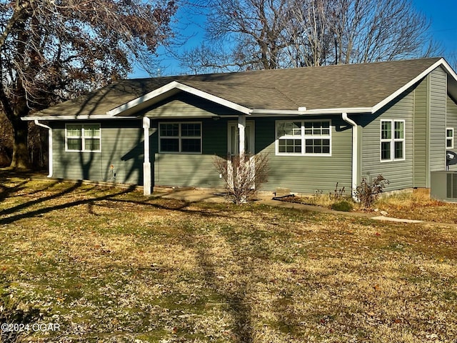 ranch-style home with a shingled roof, a front yard, and cooling unit