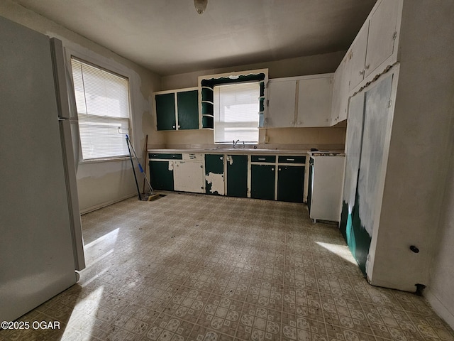 kitchen featuring light countertops, plenty of natural light, light floors, and freestanding refrigerator