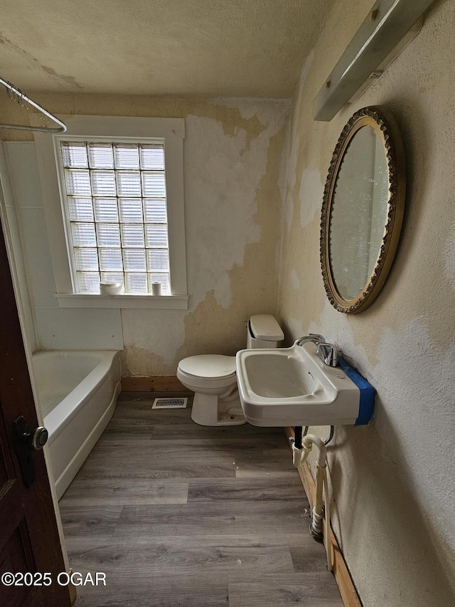 bathroom featuring wood finished floors, toilet, visible vents, and a sink