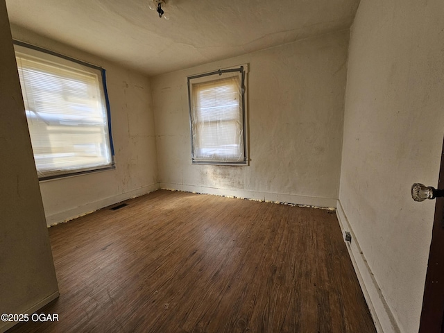 unfurnished room with wood finished floors, visible vents, and baseboards