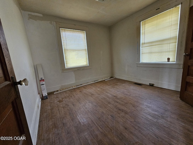 spare room featuring visible vents, baseboards, and wood finished floors