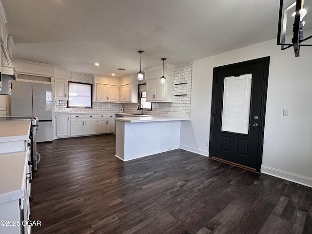 kitchen featuring light countertops, backsplash, dark wood-type flooring, white cabinetry, and a peninsula