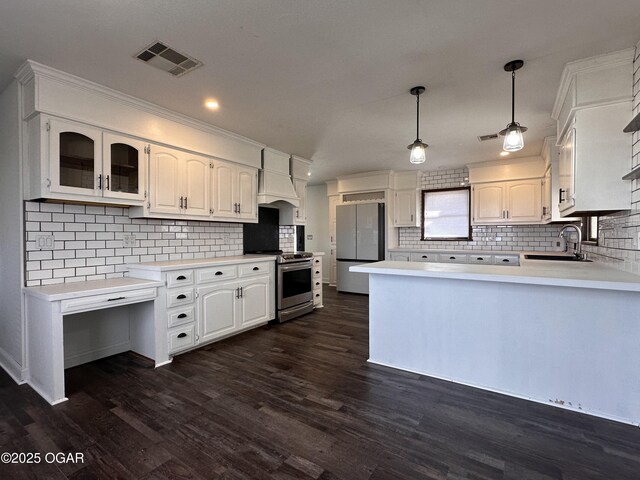 kitchen with stainless steel appliances, premium range hood, a peninsula, a sink, and visible vents