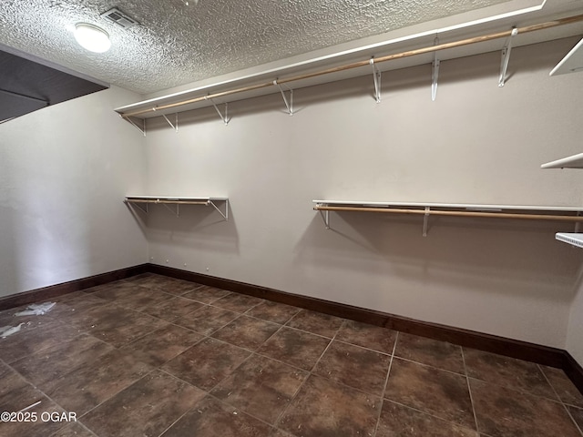 walk in closet with visible vents and dark tile patterned floors