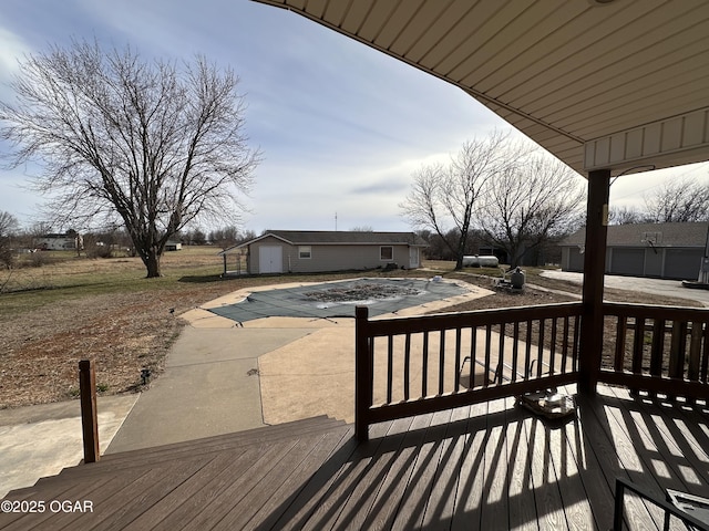 wooden deck with a covered pool, a patio, and an outdoor structure