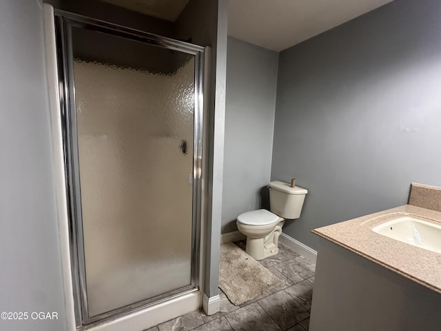 bathroom featuring a stall shower, vanity, toilet, and baseboards