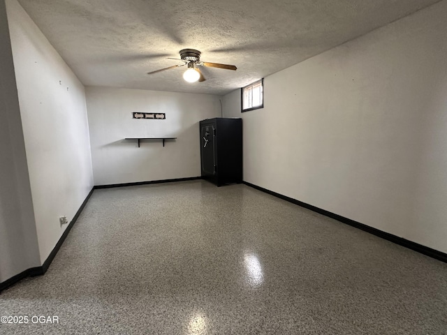 empty room with ceiling fan, a textured ceiling, baseboards, and speckled floor