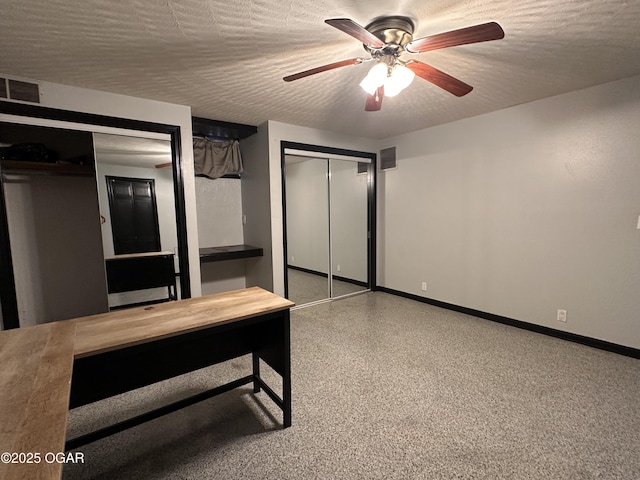 interior space featuring a textured ceiling, speckled floor, visible vents, baseboards, and two closets