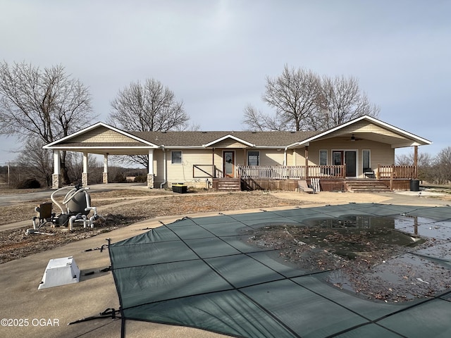 rear view of house with a carport, a covered pool, and a ceiling fan