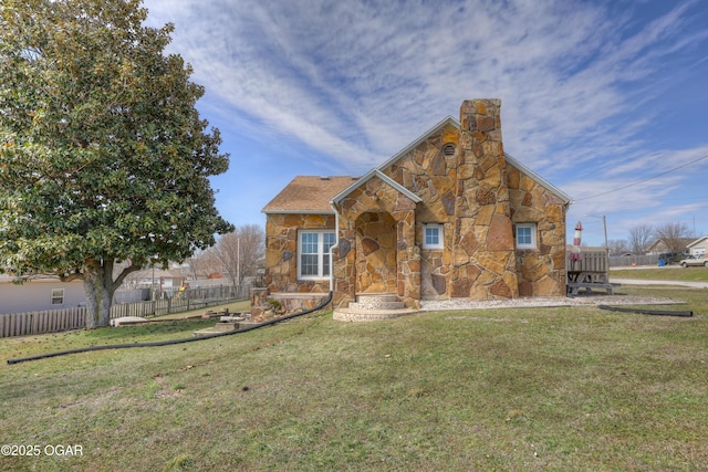 view of front facade with a front yard, stone siding, fence, and a chimney