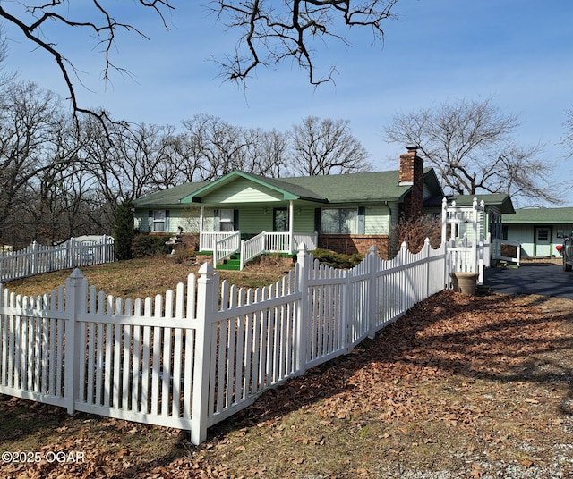 view of front of property featuring brick siding, a porch, a chimney, and a fenced front yard