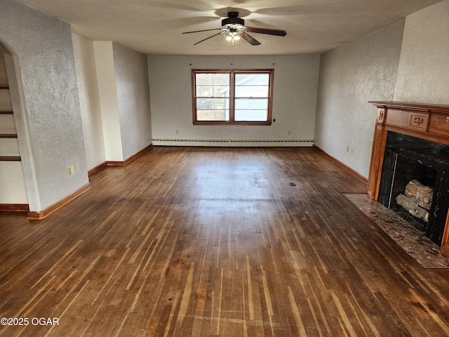 unfurnished living room with a textured wall, baseboard heating, a fireplace with flush hearth, dark wood-type flooring, and a ceiling fan