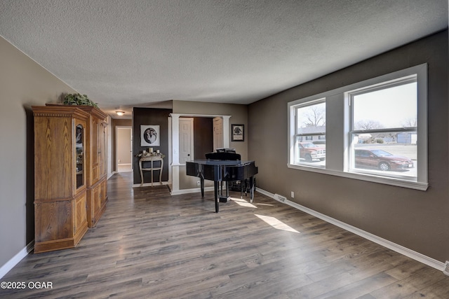 unfurnished office featuring a textured ceiling, baseboards, and wood finished floors