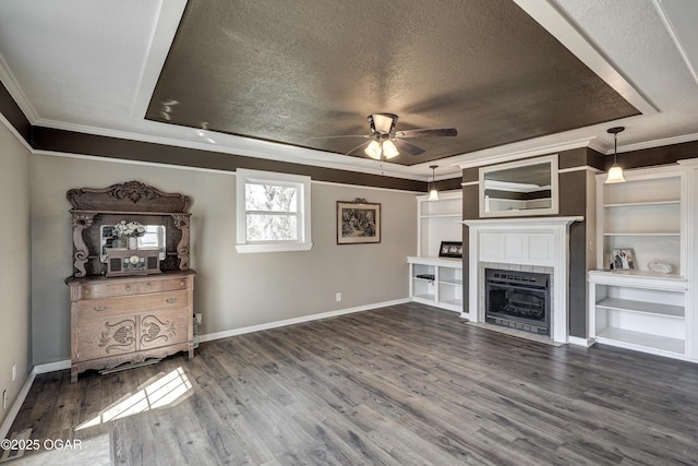 unfurnished living room with a tray ceiling, dark wood-style flooring, ornamental molding, ceiling fan, and a textured ceiling