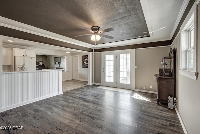 unfurnished living room featuring baseboards, a ceiling fan, dark wood-style floors, a textured ceiling, and crown molding