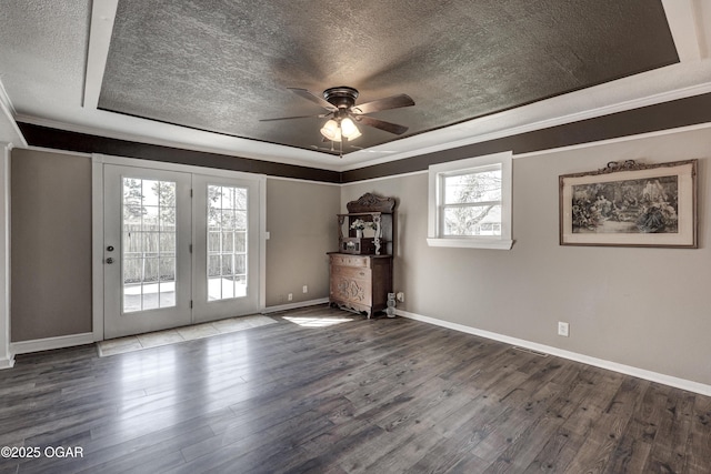 unfurnished room featuring a raised ceiling, crown molding, a textured ceiling, and wood finished floors