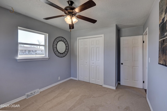 unfurnished bedroom with a textured ceiling, a closet, carpet, and visible vents