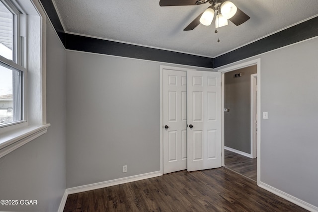 unfurnished bedroom featuring a textured ceiling, a closet, baseboards, and dark wood-type flooring