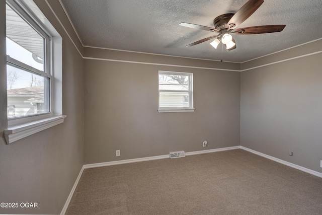 carpeted empty room with a ceiling fan, visible vents, a textured ceiling, and baseboards