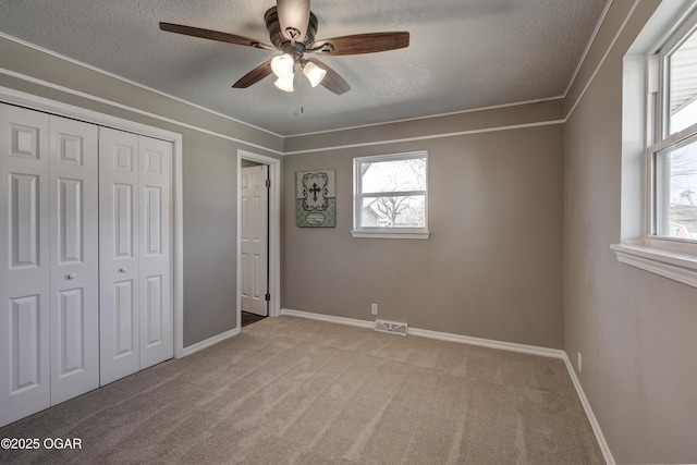 unfurnished bedroom featuring light carpet, a textured ceiling, a closet, and visible vents