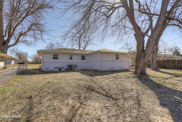 back of property with central air condition unit, fence, a lawn, and brick siding