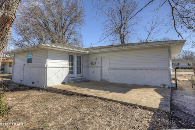 view of front of house with entry steps, brick siding, crawl space, and a patio area