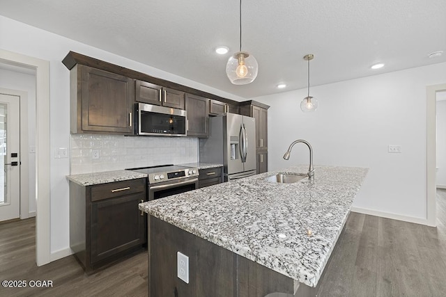 kitchen with a sink, decorative backsplash, appliances with stainless steel finishes, and dark wood-style floors