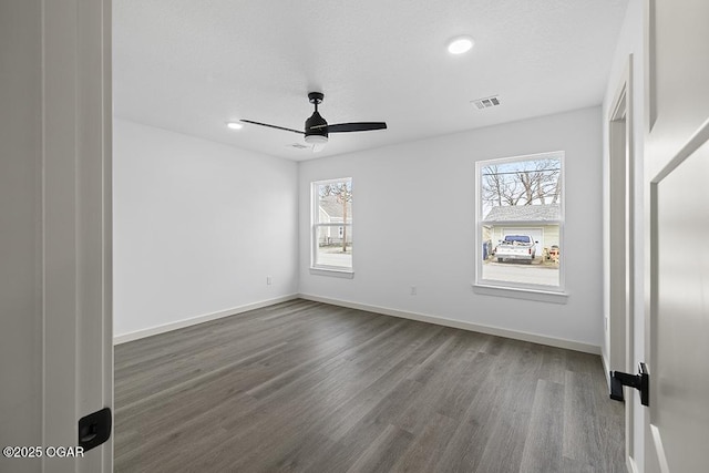 unfurnished bedroom with visible vents, multiple windows, baseboards, and wood finished floors