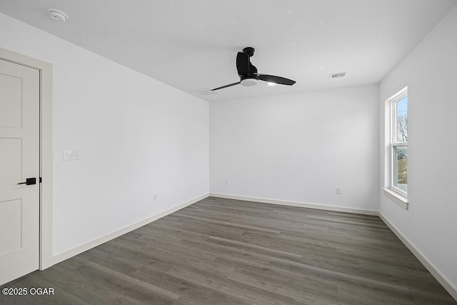 unfurnished room with visible vents, baseboards, dark wood-type flooring, and a ceiling fan