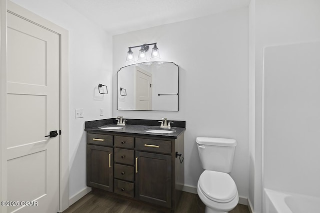 full bath with a sink, toilet, wood finished floors, and double vanity