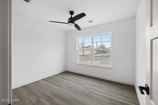 spare room featuring visible vents, ceiling fan, baseboards, and wood finished floors