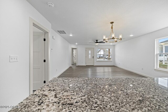 unfurnished room with a wealth of natural light, a chandelier, visible vents, and wood finished floors