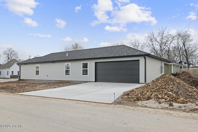 view of front of home with a garage, driveway, and a shingled roof