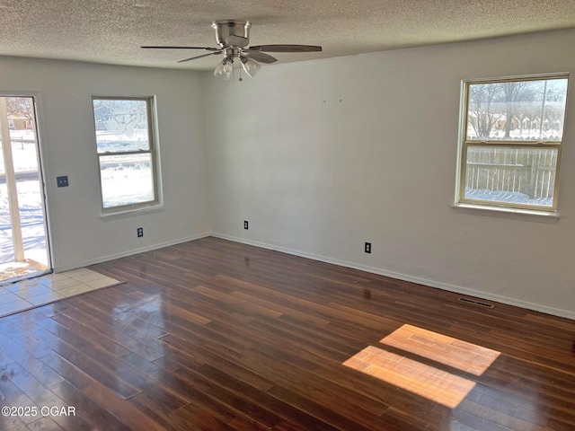 unfurnished room featuring a wealth of natural light, visible vents, a textured ceiling, and wood finished floors