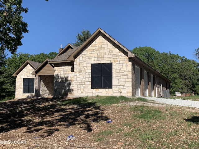 view of front of house with a garage, a chimney, and gravel driveway