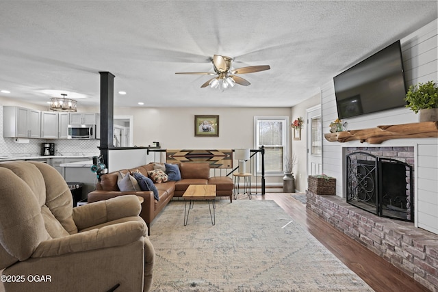 living area with a textured ceiling, wood finished floors, recessed lighting, a fireplace, and ceiling fan