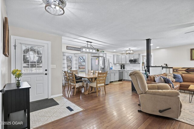 living area with a notable chandelier, baseboards, a textured ceiling, and hardwood / wood-style floors