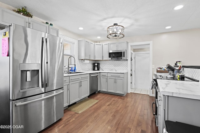 kitchen with a sink, dark wood finished floors, gray cabinets, and stainless steel appliances