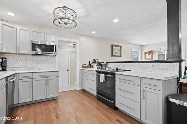 kitchen with backsplash, gray cabinetry, recessed lighting, light wood-style flooring, and stainless steel appliances