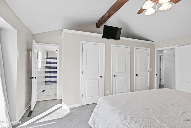 bedroom with two closets, baseboards, lofted ceiling with beams, carpet flooring, and ensuite bathroom