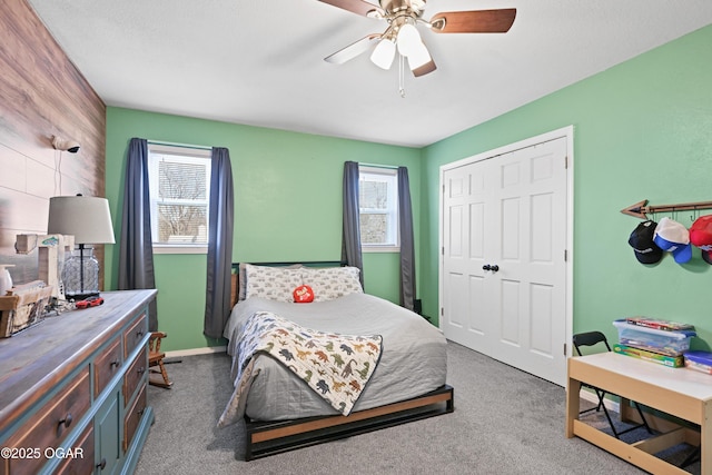 carpeted bedroom with a closet, baseboards, and a ceiling fan