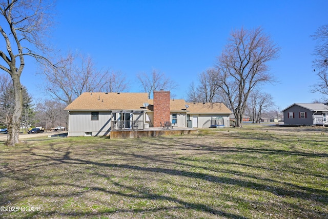 rear view of house with a lawn, a chimney, and a deck