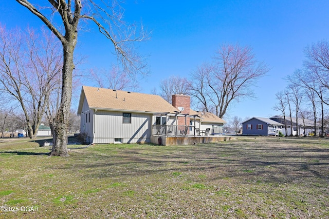 back of property with a yard, a deck, and a chimney