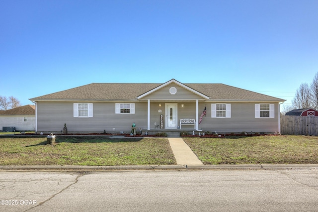 ranch-style house featuring cooling unit, fence, roof with shingles, a porch, and a front lawn