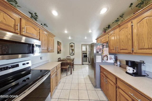 kitchen with light countertops, recessed lighting, appliances with stainless steel finishes, brown cabinets, and light tile patterned flooring