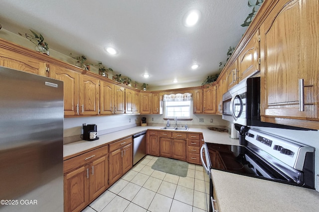 kitchen with light countertops, brown cabinets, appliances with stainless steel finishes, and a sink